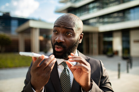 Businessman recording voice message outside office building