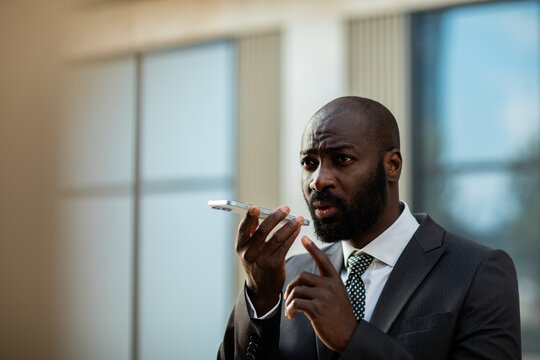 Businessman using voice command on smartphone outside office