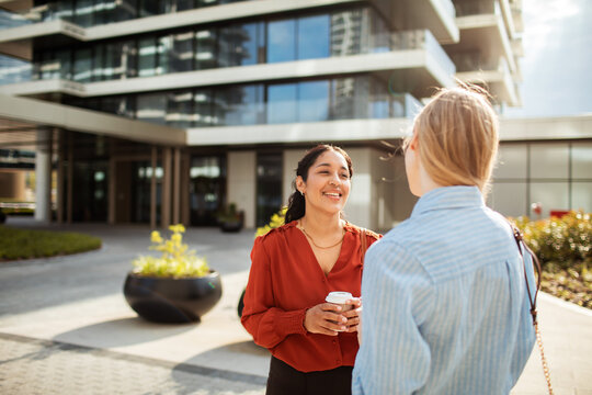 Two businesswomen chatting outside modern office building