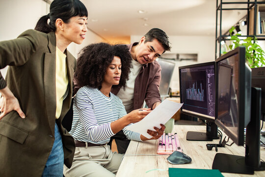 Coworkers reviewing data charts at modern office desk
