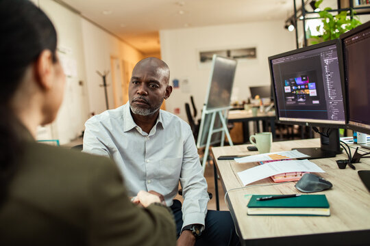 Colleagues shaking hands during meeting in modern creative office