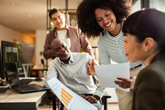 Diverse coworkers collaborating on reports in modern office
