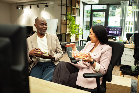 Coworkers chatting over lunch in modern office