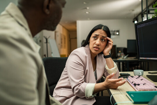 Concerned businesswoman discussing project at office desk