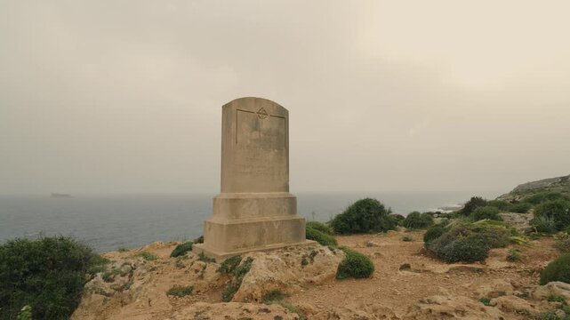 Slow push-in to Sir Walter Norris Congreve memorial on Malta coastline with Mediterranean Sea and Filfla island in background