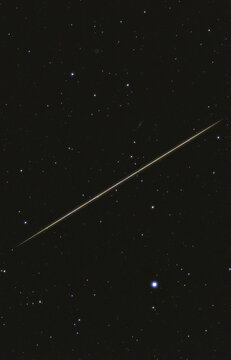 Light trail crossing starry sky near bright star Merak.