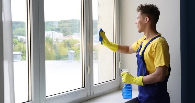 Man washing window with rag and detergent indoors