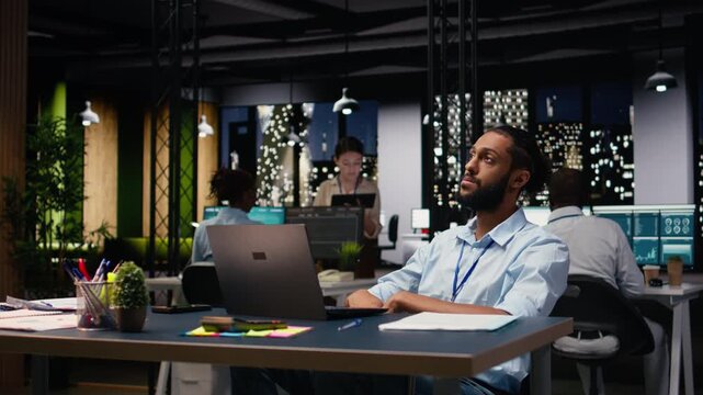 Middle Eastern man in wheelchair brainstorming ideas and solutions for a complex project, working late in office. Manager analyzes data for business intel, disability-friendly inclusive workspace.