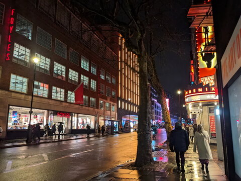 Pedestrians walking past the iconic Foyles bookshop and Phoenix Theatre in London West End
