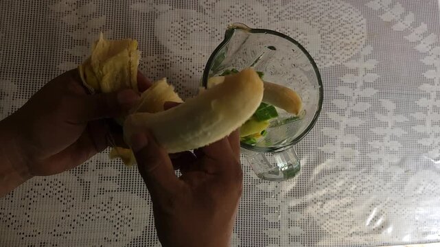 Peeling Fresh Tabasco Banana And Dropping It Into Smoothie Blender
