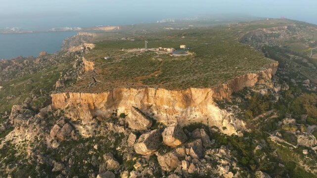Aerial drone approach toward rugged limestone coastal cliffs on western Malta coastline with dramatic terrain reveal