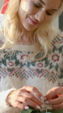 Vertical video: Spotting green-wrapped gift she in sweater at home untying bow preparing to reveal