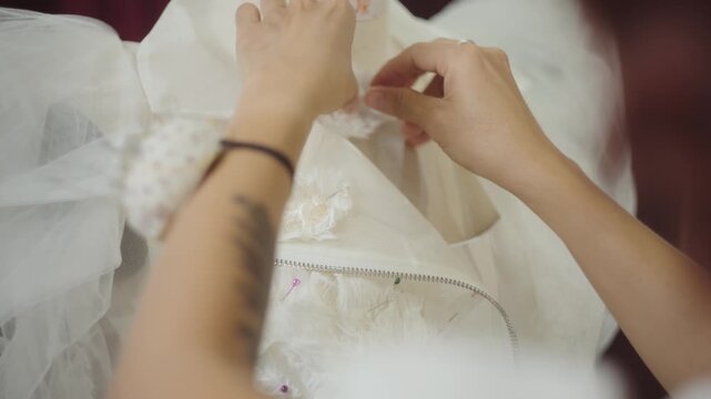 Bridal fashion designer pinning decorative floral appliques onto couture wedding dress