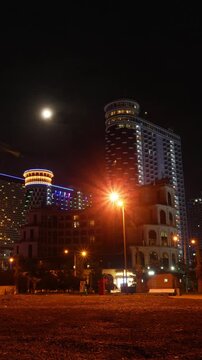 Vertical video glowing Batumi panorama from beach. Timelapse of turning off illumination of modern skyscrapers in Batumi at night. Capital of Adjara