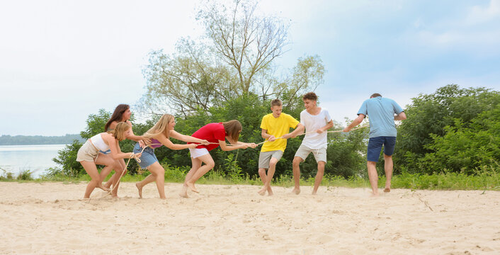 A group of teenage students are having fun on the beach playing tug of war