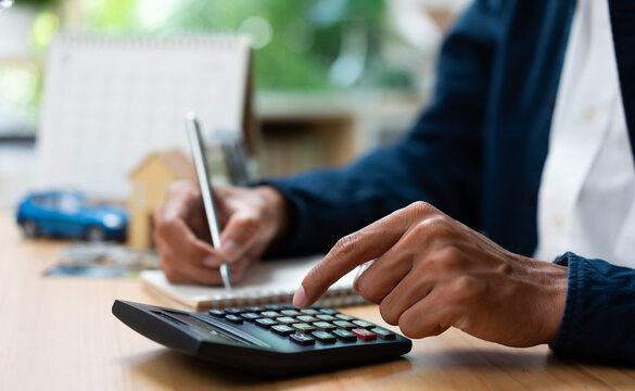 Businessman calculating car insurance and financial planning with calculator and documents at office desk.