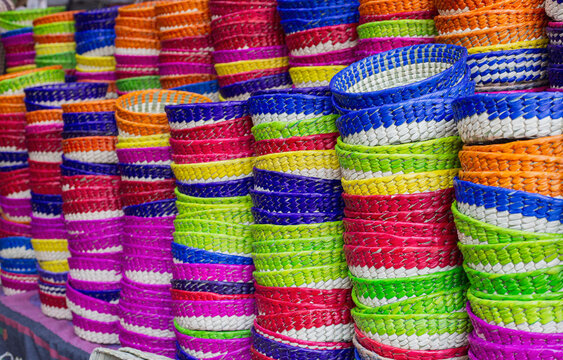 Cestos de mimbre tejidos a mano en m&uacute;ltiples colores brillantes, apilados verticalmente en exhibici&oacute;n