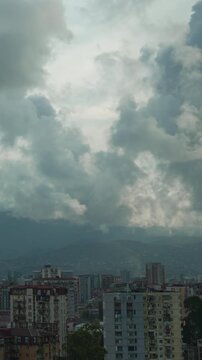 Storm clouds are scudding over a city at the foot of the Caucasus Mountains timelapse vertical video. Storm warning, climate change, environmental protection. Problem of urban air pollution