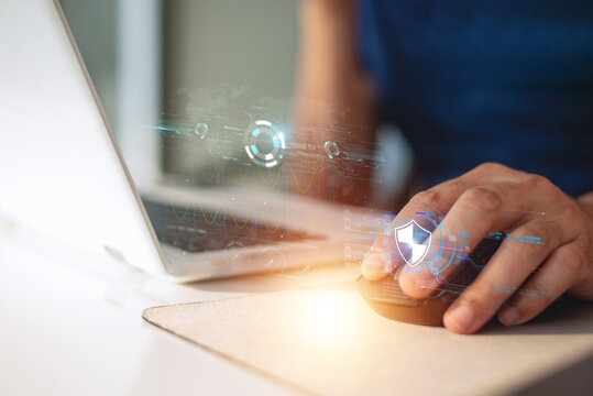 Hand using computer mouse with glowing cybersecurity shield hologram on laptop.