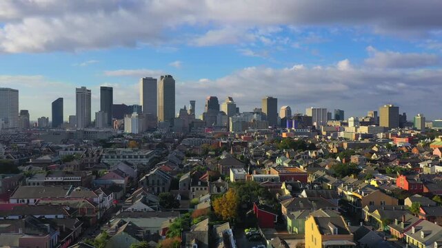 Aerial view of New Orleans skyline with colorful houses in foreground during golden hour cinematic drone footage.