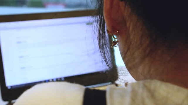 실내 노트북 화면 작업 여성 뒷모습 귀걸이 인물 프로필 자재: 귀걸이를 착용한 여성이 책상 앞 노트북 모니터 화면을 바라보며 업무나 웹서핑에 집중하는 모습을 뒤에서 포착한 클로즈업 영상입니다. 목덜미와 어깨를 담았으며, 프리랜서 재택근무, 오피스 직장인 소통, 일상적인 컴퓨터 사용, 디지털 노마드 및 1인 기업 콘셉트의 실감 나는 인서트 숏을 상징합니다.