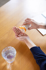 Obraz premium Close-up of woman's hands taking pills out of bottle
