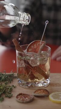 Bartender Pouring Clear Liquid into Botanical Cocktail with Cinnamon
