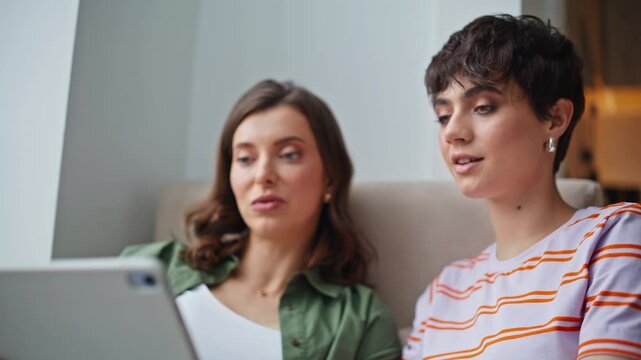 Relaxed sisters video meeting talking to tablet webcam sitting cozy home closeup