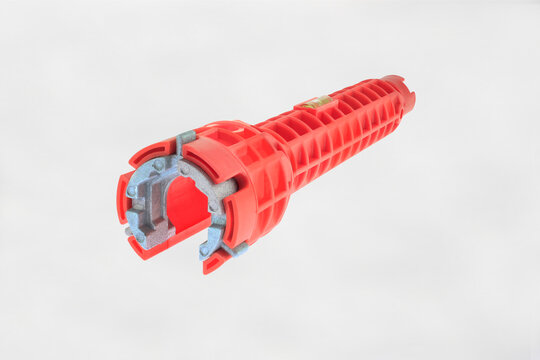 Red sink installer wrench multifunction faucet and tool isolated on white background. Industrial hand tool for plumbing, pipe fitting, construction, mechanical installation work, ergonomic tool work.