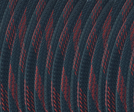 Dark blue cable with red diagonal stripes. Texture shows woven fibers in closeup view Pattern repeats uniformly along curved surface, detailed macro texture showing diagonal weave durability flexible
