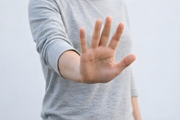 Obraz premium Man in Gray Long Sleeve Shirt Making Stop Gesture Against Neutral Wall Background