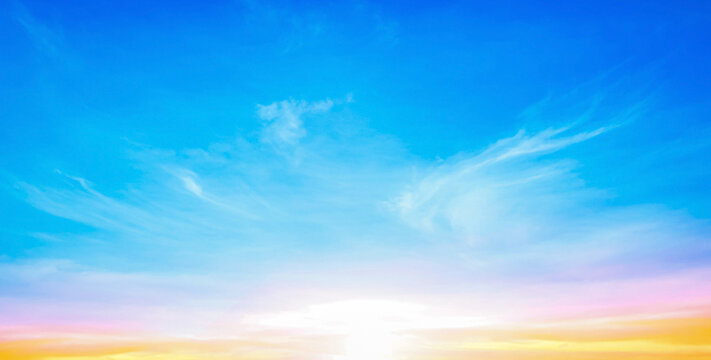 Beautiful bright golden sunset sky background with vibrant blue and romantic pink pastel clouds for inspirational nature wallpaper panorama