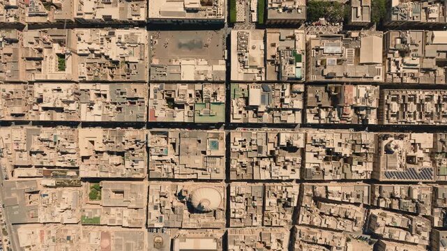 Top down aerial drone view over Valletta, Malta showing grid-like historic street pattern and limestone buildings forming geometric urban blocks in fortified city. 