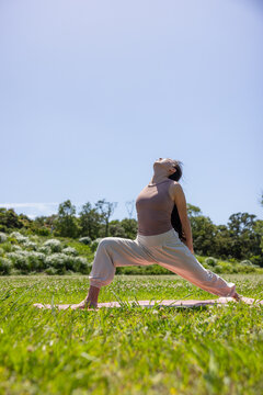 Woman doing backward bend yoga pose outside under sky