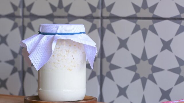Natural probiotics. Milk kefir fermentation process inside a glass jar with a cloth lid