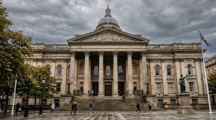 Obraz premium Neoclassical civic building facade with columns and dome under overcast sky with pedestrians on wet paved plaza in urban public square