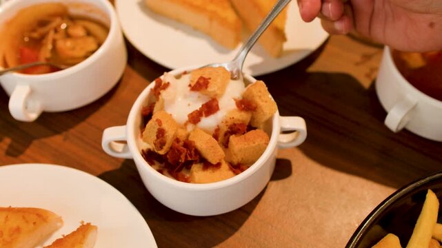 Close Up of Person Eating Creamy Soup with Croutons and Bacon