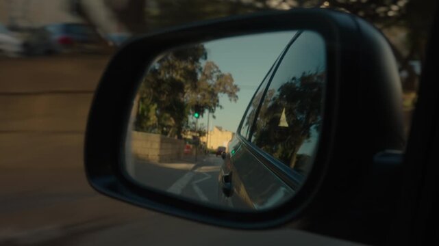 Cinematic car mirror shot reflecting limestone bastions and Maltese architecture while driving through Malta. Cinematic travel footage captured from inside moving car Malta, focusing on a side mirror