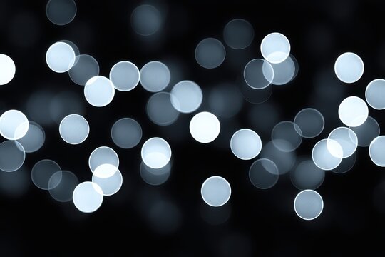Abstract bokeh background with soft white lights on a dark backdrop.