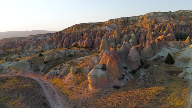 Goreme, Nevsehir, Turkey. Devrent Valley fairy chimneys and eroded volcanic tuff formations, aerial view at golden hour with warm light sculpting the mineral-rich landscape. Aerial View