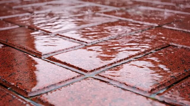 Raindrops falling on terracotta tiles creating ripples and splashes.