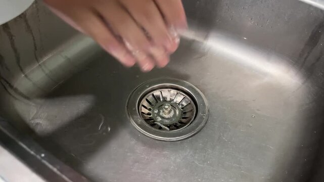 Close Up View of Man Applying Soap and Lathering His Hands Over Stainless Steel Kitchen Sink