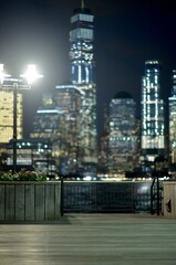 Obraz premium Calm Seaside Walkway With Soft City Lights And Distant Skyscraper Illumination new york