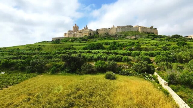 Drone view of Mdina, Malta known as the Silent City. Historic fortified skyline above green surroundings and elevated Mediterranean terrain.