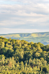 Obraz premium Layers of green mountains and hills in the haze during sunset. Panoramic View of Green hills and Meadow.