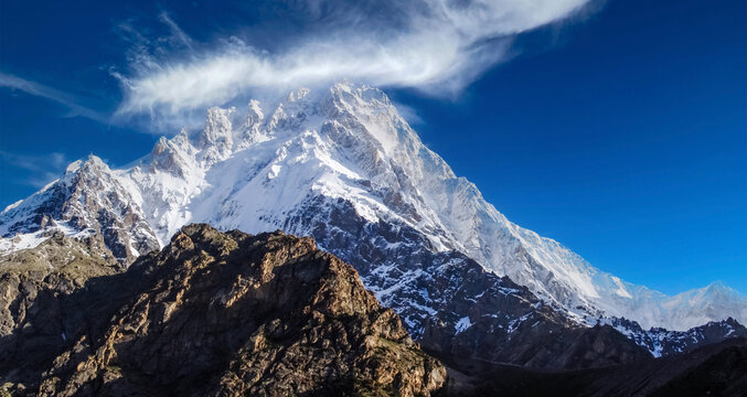 A dramatic close-up of crampon tracks winding through fresh powder snow toward the steep slopes of Nanga Parbat