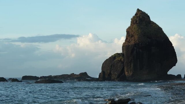 Beautiful ocean scenery with large rock formations and sparkling sea water during a sunny day at a tropical beach in Jember, Indonesia.