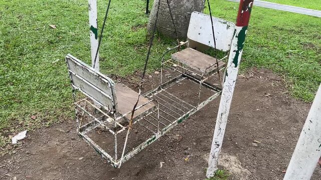 Empty double metal swing moving in a park