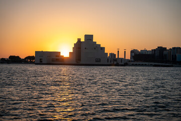 Obraz premium Sunset over a modern building by the water's edge.