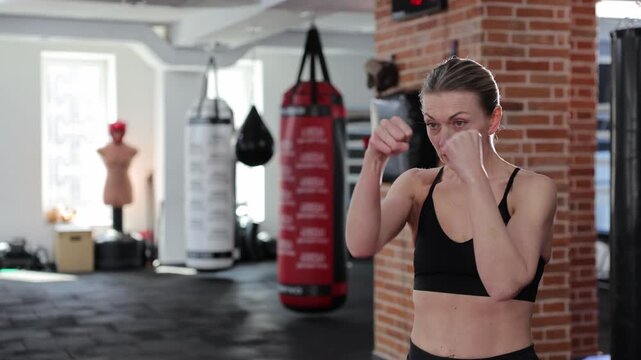 Determined woman practicing boxing punches in gym